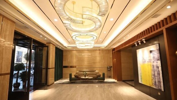 A spacious lobby with a modern chandelier, a sofa, and a large abstract painting on the wall. - Chengtoushan International Hotel (Li County)
