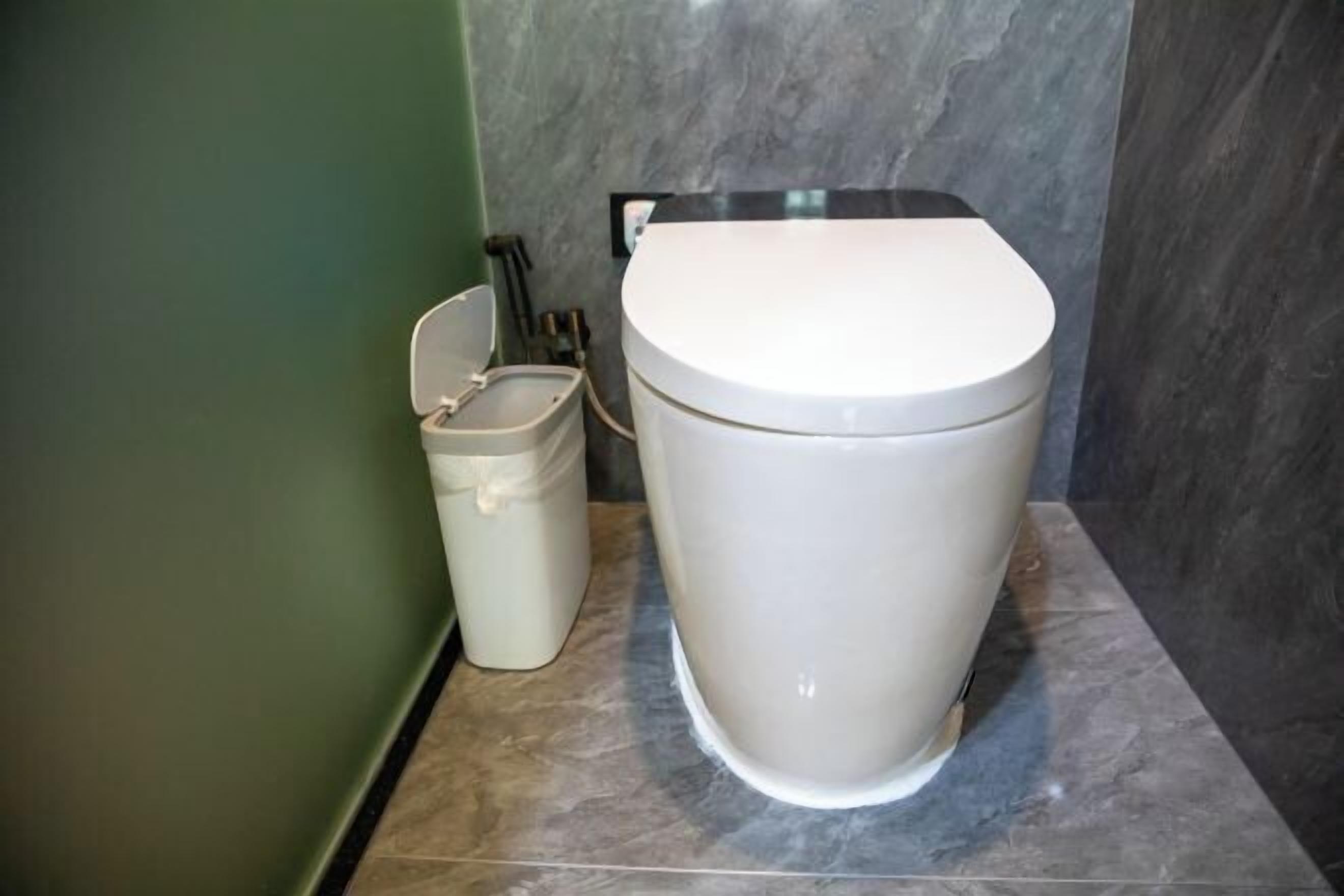 Un baño con inodoro y un cubo de basura.