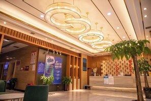 Zona de recepción de hotel con diseño moderno, que incluye un mostrador de recepción, área de estar e iluminación decorativa.