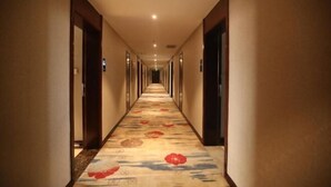 A hotel hallway with a carpeted floor, doors on both sides, and a light fixture on the ceiling. - Chengtoushan International Hotel (Li County)