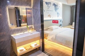 A modern hotel room with a large bed, a bedside table with a lamp, a large mirror, and a world map on the wall. - Chengtoushan International Hotel (Li County)