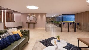 Una hall moderna con un divano verde, un tavolino da caffè e una reception.