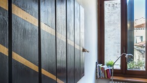 A room with a large wooden wardrobe, a window with a view of buildings, and a radiator. - ACQUARELLO, SPACIOUS APARTMENT IN THE HEART OF VENICE (Venise)