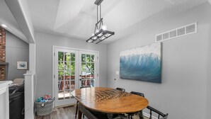 A dining area with a round wooden table, black chairs, a ceiling light fixture, and a large abstract painting on the wall. - KC Backyard Vacation (Kansas City)