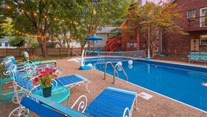A backyard with a swimming pool, blue lounge chairs, and a red fence. - KC Backyard Vacation (Kansas City)
