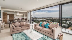 A modern living room with two sofas, a coffee table, and a large window offering a city view. - Apartment (Zapopan)