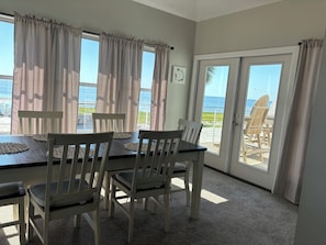 A room with a table and chairs facing a large window with a view of the beach. - Reel Em Inn Bay Front House With boat ramp (port saint joe/simmons bayou)