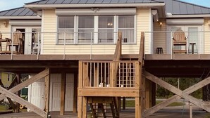 A two-story house with a balcony, a wooden deck, and a garage. - Reel Em Inn Bay Front House With boat ramp (port saint joe/simmons bayou)