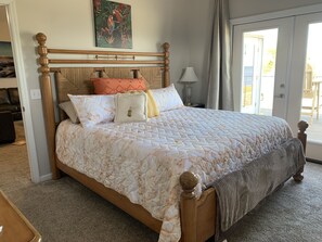 A bedroom with a large bed, a wooden headboard, and a painting above it. - Reel Em Inn Bay Front House With boat ramp (port saint joe/simmons bayou)