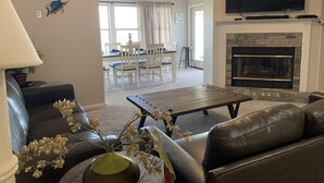 A living room with a fireplace, a television, a dining area with chairs, and a ceiling fan. - Reel Em Inn Bay Front House With boat ramp (port saint joe/simmons bayou)