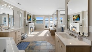 A modern bathroom with dual sinks, a large mirror, and a view of the ocean. - Relaxing 4 bed, 4 bath, + private studio lakefront home on Lake Stevens! (Lake Stevens)