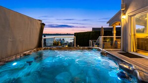 A hot tub area with a view of the water and a deck. - Relaxing 4 bed, 4 bath, + private studio lakefront home on Lake Stevens! (Lake Stevens)