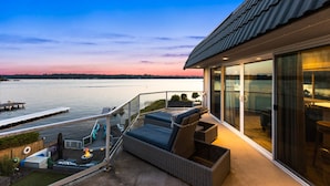 A balcony with a view of a body of water, wicker furniture, and a glass door leading to an interior space. - Relaxing 4 bed, 4 bath, + private studio lakefront home on Lake Stevens! (Lake Stevens)