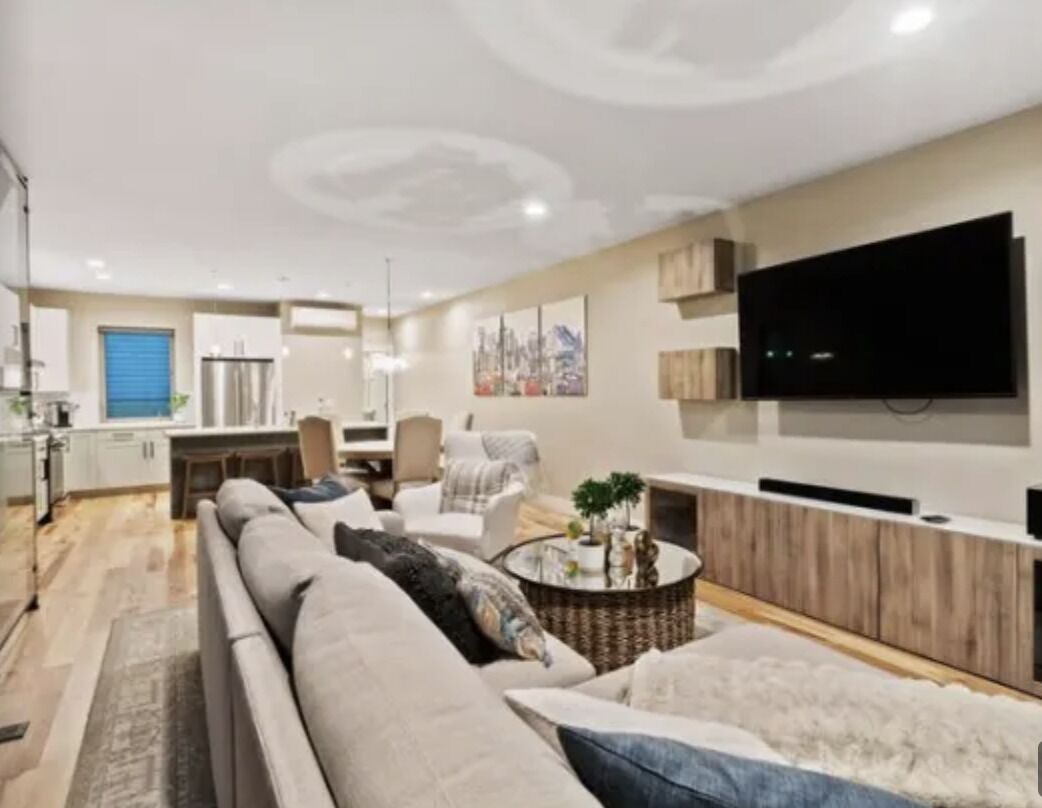 A modern living room with a sofa, coffee table, and a flat-screen TV mounted on the wall.
