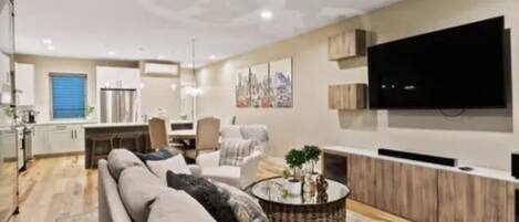 A modern living room with a sofa, coffee table, and a flat-screen TV mounted on the wall.