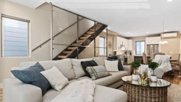 A modern living room with a sofa, a coffee table, and a staircase. - Luxury Alki Beach Townhome w/ Large Private Rooftop & Amazing Views! (Seattle)