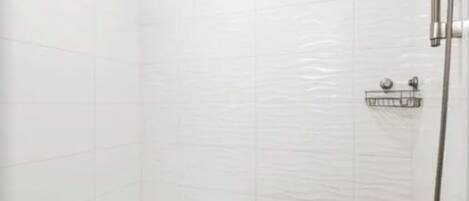 A bathroom with white tiled walls and a shower area.