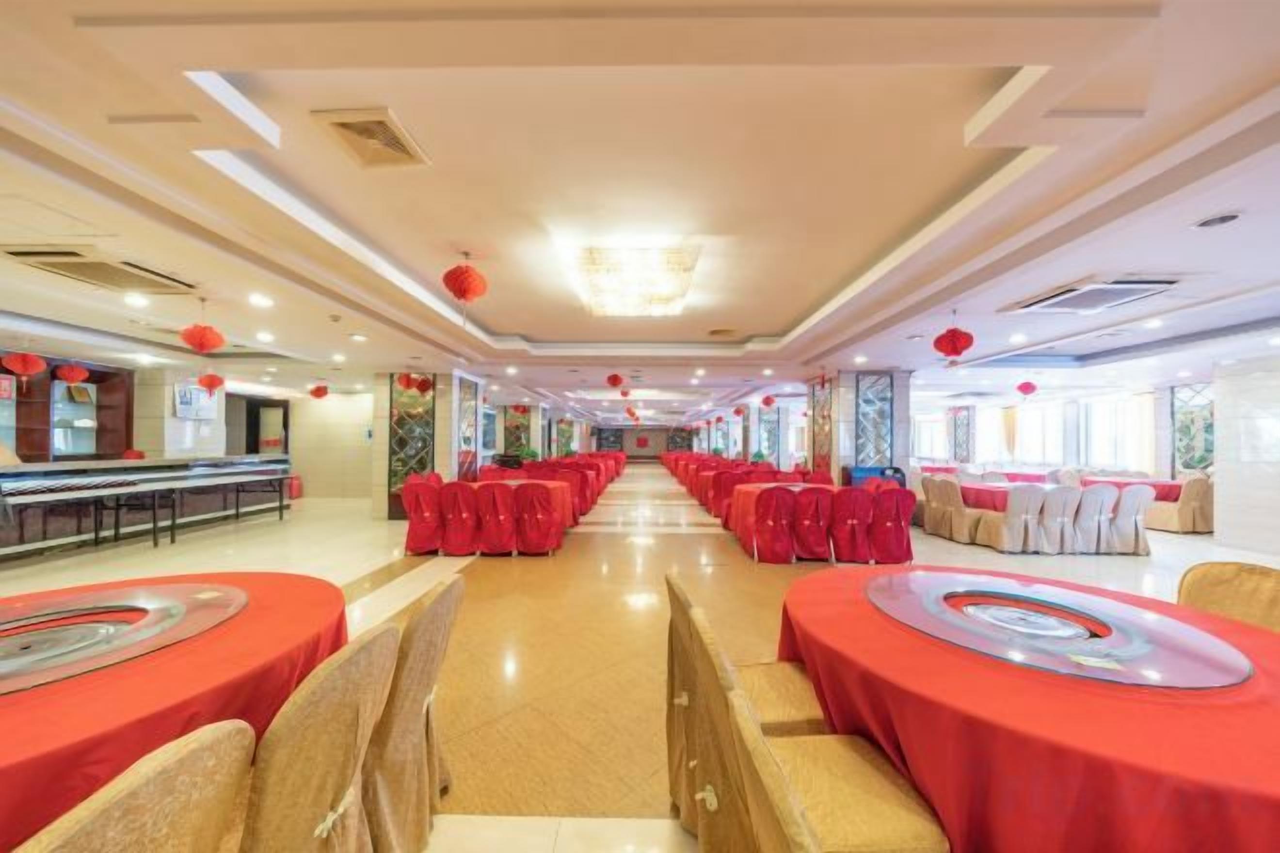 A banquet hall with rows of tables and chairs, a long counter, and a chandelier.