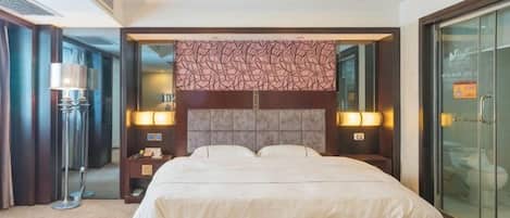 Habitación de hotel con una cama grande, lámparas de noche, una mesita de noche y un ventanal de cristal que da a un balcón.