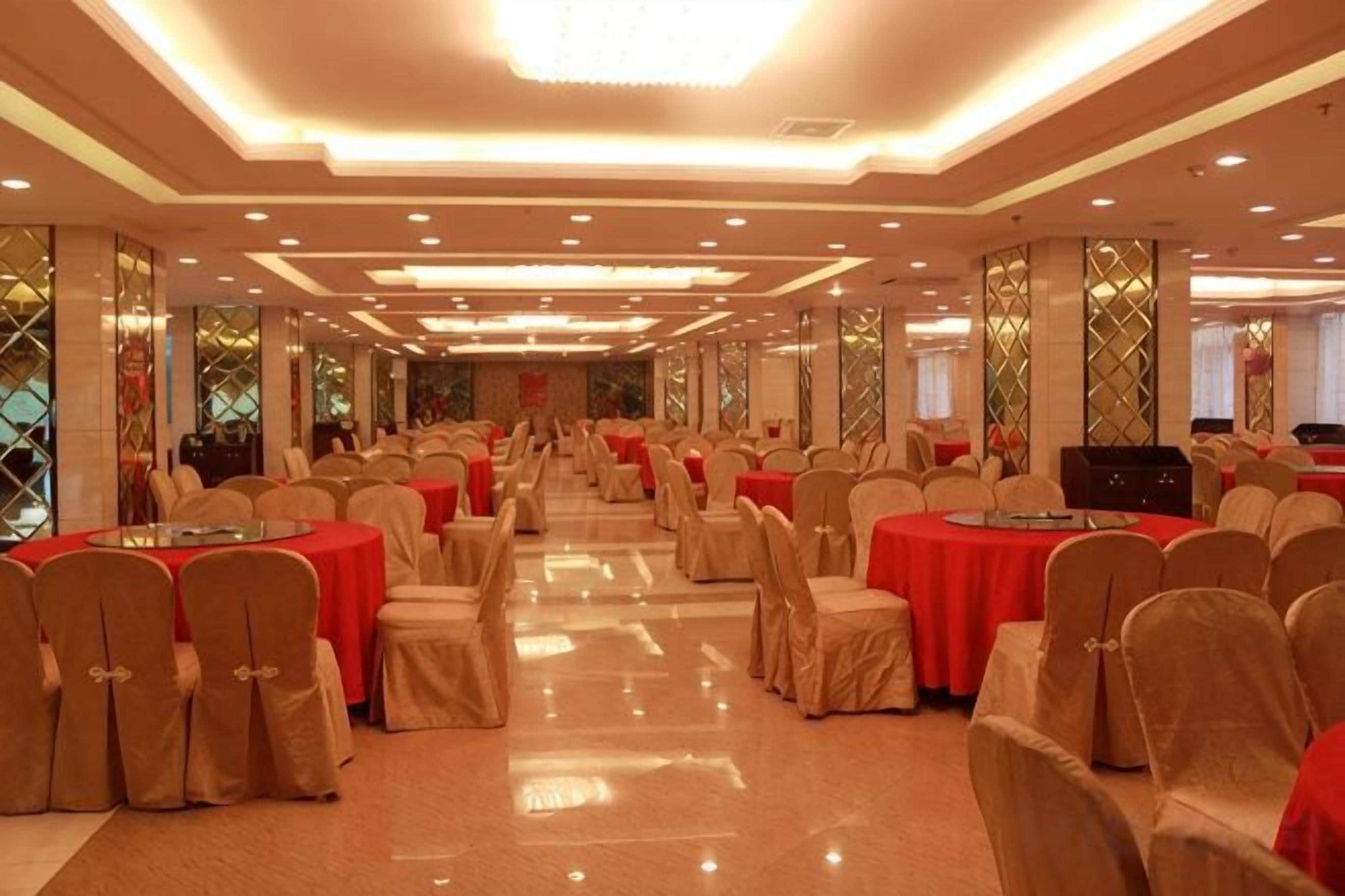 A banquet hall with round tables, chairs, and a stage.
