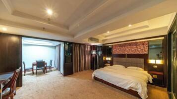 Habitación de hotel con una cama grande, un escritorio con sillas, un televisor y un minibar.