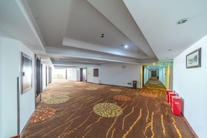 A hotel corridor with a patterned carpet, doors, and a red luggage trolley. - Ling Nan International Hotel (Xing'an County)