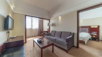 Una habitación de hotel con sofá, mesa de centro, televisor, cama y escritorio.