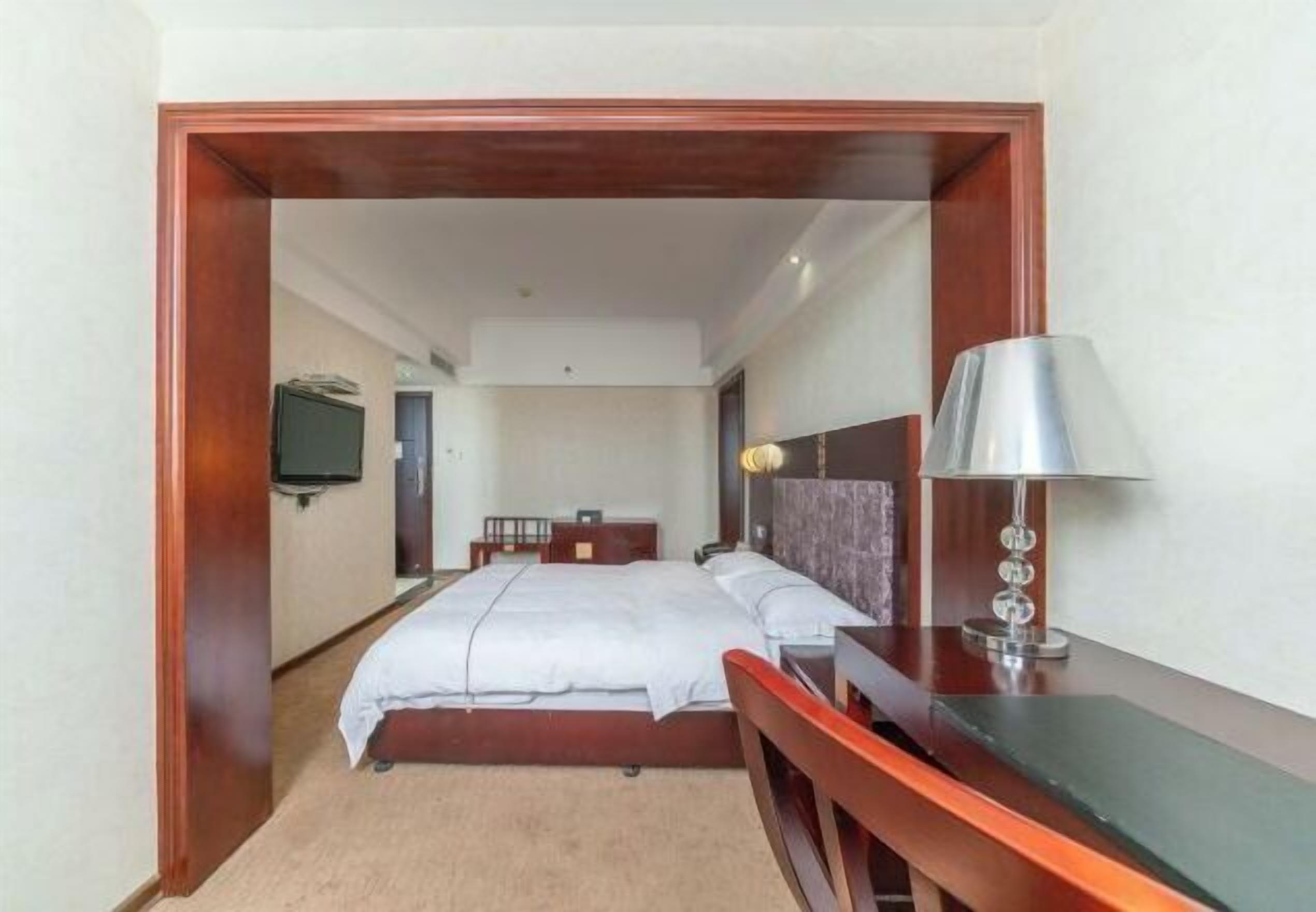 Una habitación de hotel con cama, mesita de noche, lámpara y escritorio.
