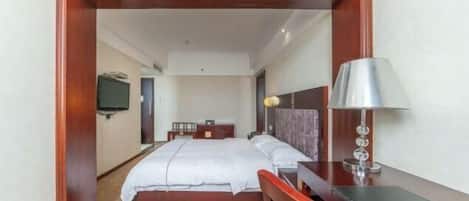 Una habitación de hotel con cama, mesita de noche, lámpara y escritorio.