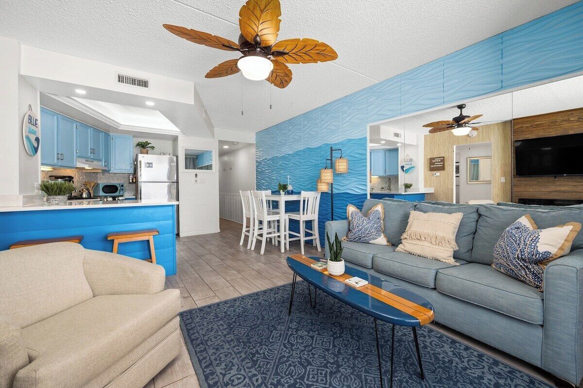 Ein modernes Wohnzimmer mit blauer Akzentwand, einem grauen Sofa und einem Couchtisch aus Holz.
