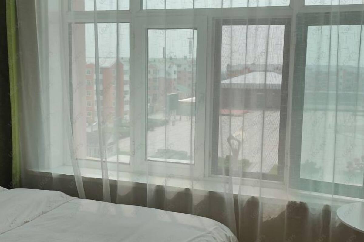 Hotellihuone, jossa on suuri ikkuna, sänky ja pyöreä pöytä.