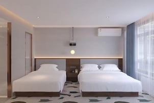 Una habitación de hotel con dos camas, una lámpara de techo y un equipo de aire acondicionado.