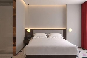 A modern hotel room with a large bed, bedside tables, and a red curtain.