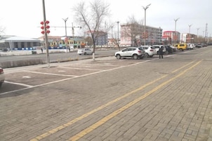 Un estacionamiento pavimentado con espacios delimitados y una senda peatonal.
