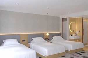 Habitación de hotel con dos camas, una mesita de noche con lámpara, un espejo y un cabecero de madera.