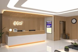 Una recepción con un mostrador, una pantalla digital, un reloj y una planta en maceta.