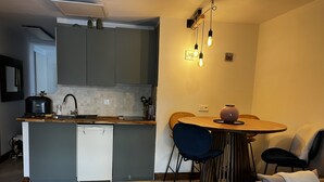 A compact kitchen with a dishwasher, a coffee maker, and a toaster. There is a dining area with a round table and two chairs. - Apartment near center 5 min walk and 5 min drive to beaches (La Croix-Valmer)