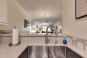 A modern kitchen with a stainless steel sink, a paper towel holder, and a blue bottle of hand soap.