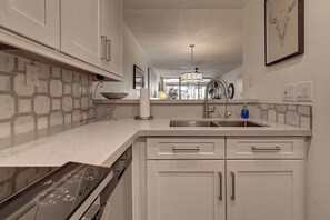 Een moderne keuken met een inbouwvaatwasser, een spoelbak en een aanrecht met een kom en een keukenrolhouder.
