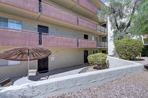 A multi-story residential building with balconies, a covered outdoor seating area, and a small garden.