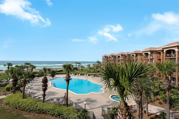 A resort with a pool, palm trees, and a view of the ocean. - BeachFront! Pool, Grill, Beach Svc! wifi, kitchen (Miramar Beach)