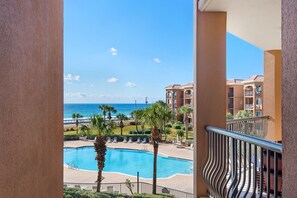 A pool area with a view of the ocean and a building with balconies. - BeachFront! Pool, Grill, Beach Svc! wifi, kitchen (Miramar Beach)
