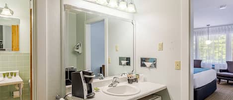 Une salle de bain d’hôtel avec un lavabo, un miroir et des luminaires.