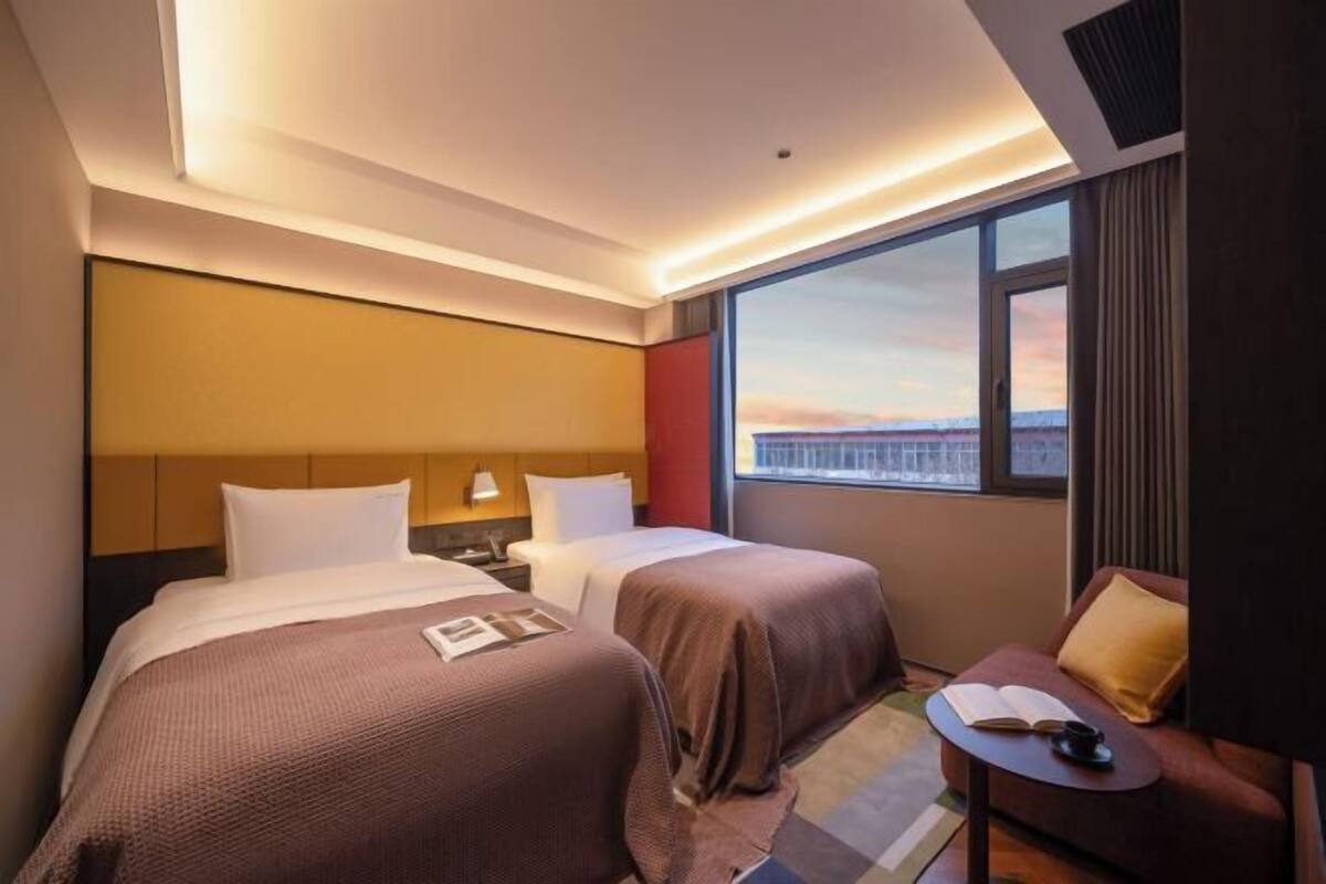 Een hotelkamer met twee bedden, een kleine tafel, een stoel en een raam met uitzicht.