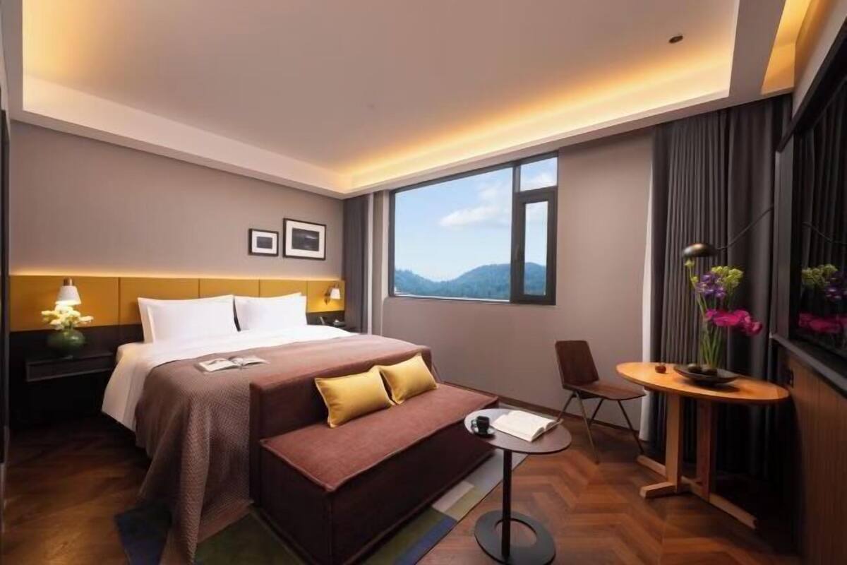 Een hotelkamer met een bed, een slaapbank, een tafeltje, een stoel en een raam met uitzicht.