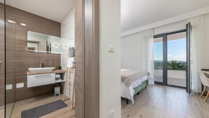 Ett modernt sovrum med en säng, ett litet skrivbord och en balkong med utsikt.