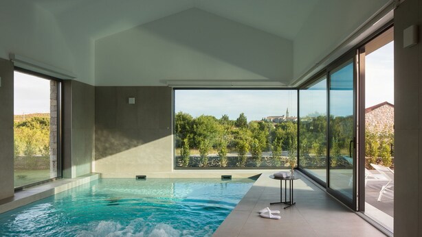 Piscina interior moderna con vistas despejadas a un paisaje montañoso a través de amplios ventanales.