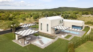 Una casa moderna con piscina, mobiliario exterior y vistas del paisaje circundante.