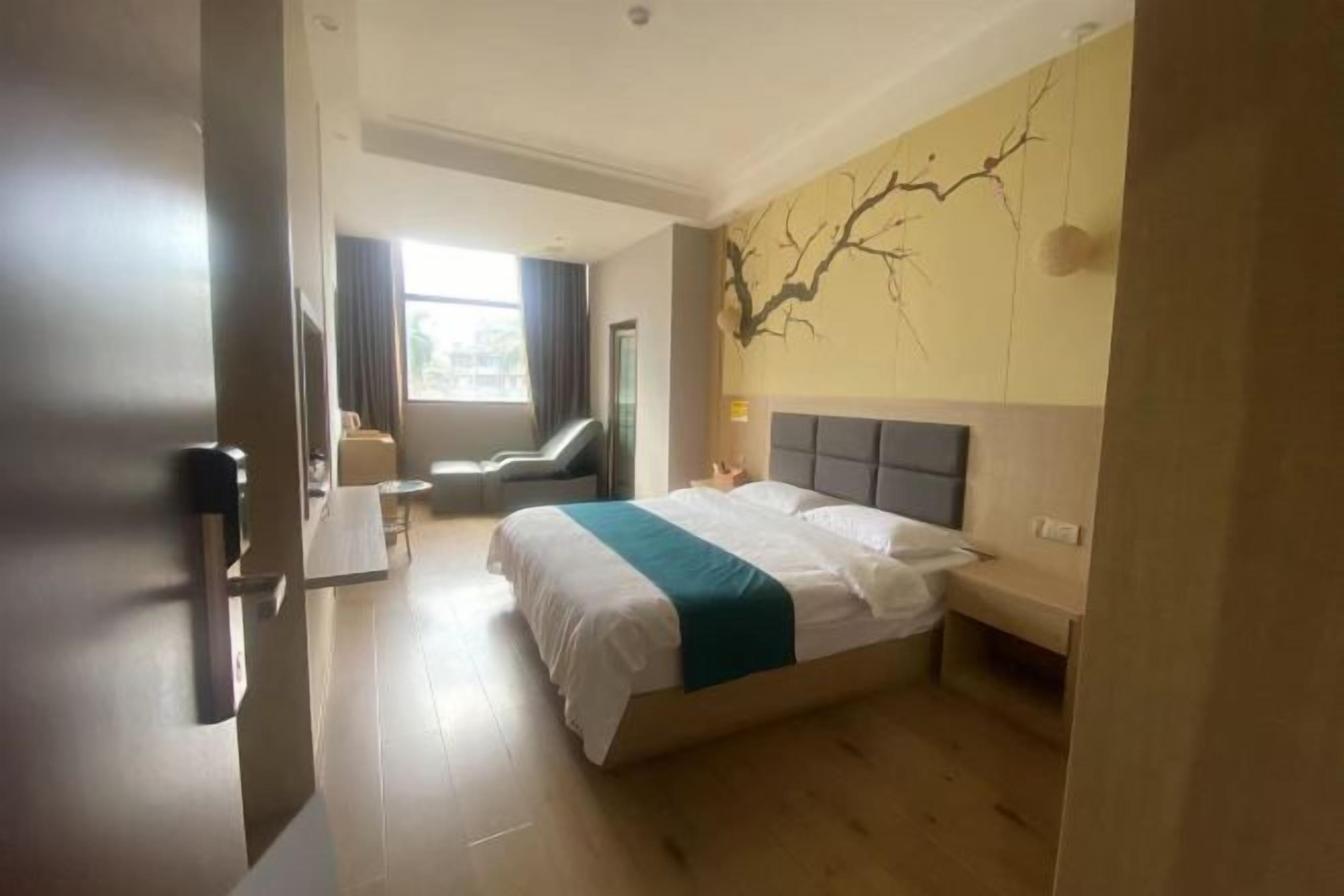 A hotel room with a large bed, a desk, a chair, and a window with curtains.