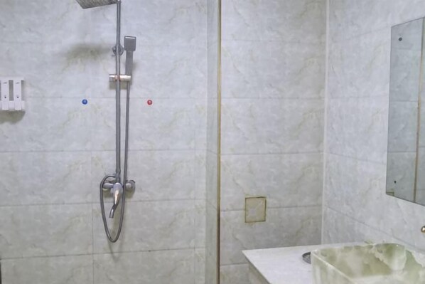 A bathroom with a shower, a sink, and a mirror. - Yintai Hotel (Menglian)